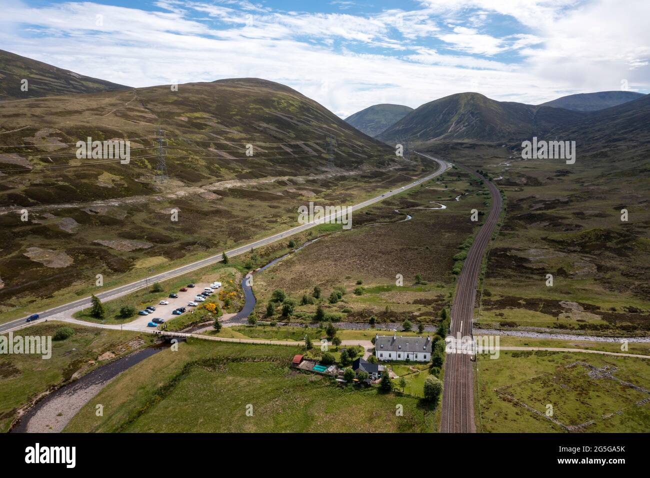 Vista aérea de la carretera principal A9 y la línea principal de ferrocarril de las tierras altas en el Puerto de Drumochter, región de Highland, Escocia, Reino Unido Foto de stock