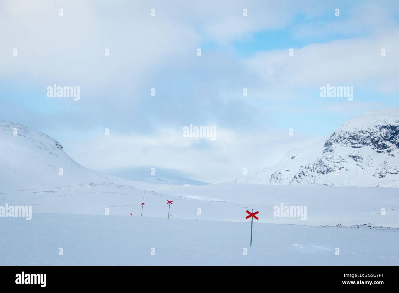 Saliendo de las cabañas de Alesjaure al amanecer mientras se raquetas de nieve Kungsleden sendero, Laponia, Suecia, 2021 de abril. Las cruces rojas marcan el camino. Foto de stock