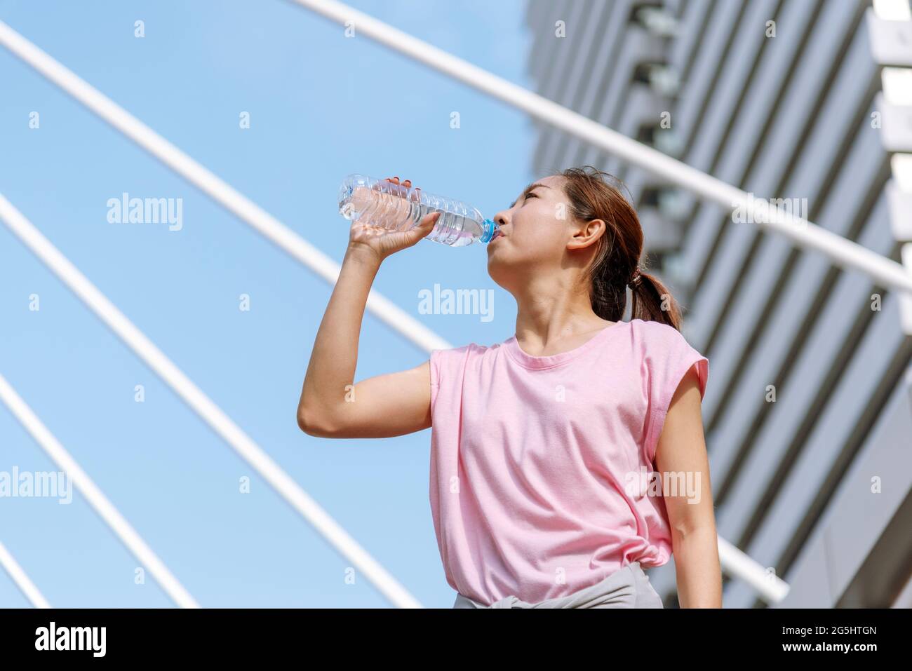 Deporte Fitness Mujeres agua potable en la ciudad moderna vestir wellness ropa  deportiva fuera. Una mujer joven hace ejercicio al aire libre en el soleado  exterior. Él Fotografía de stock - Alamy