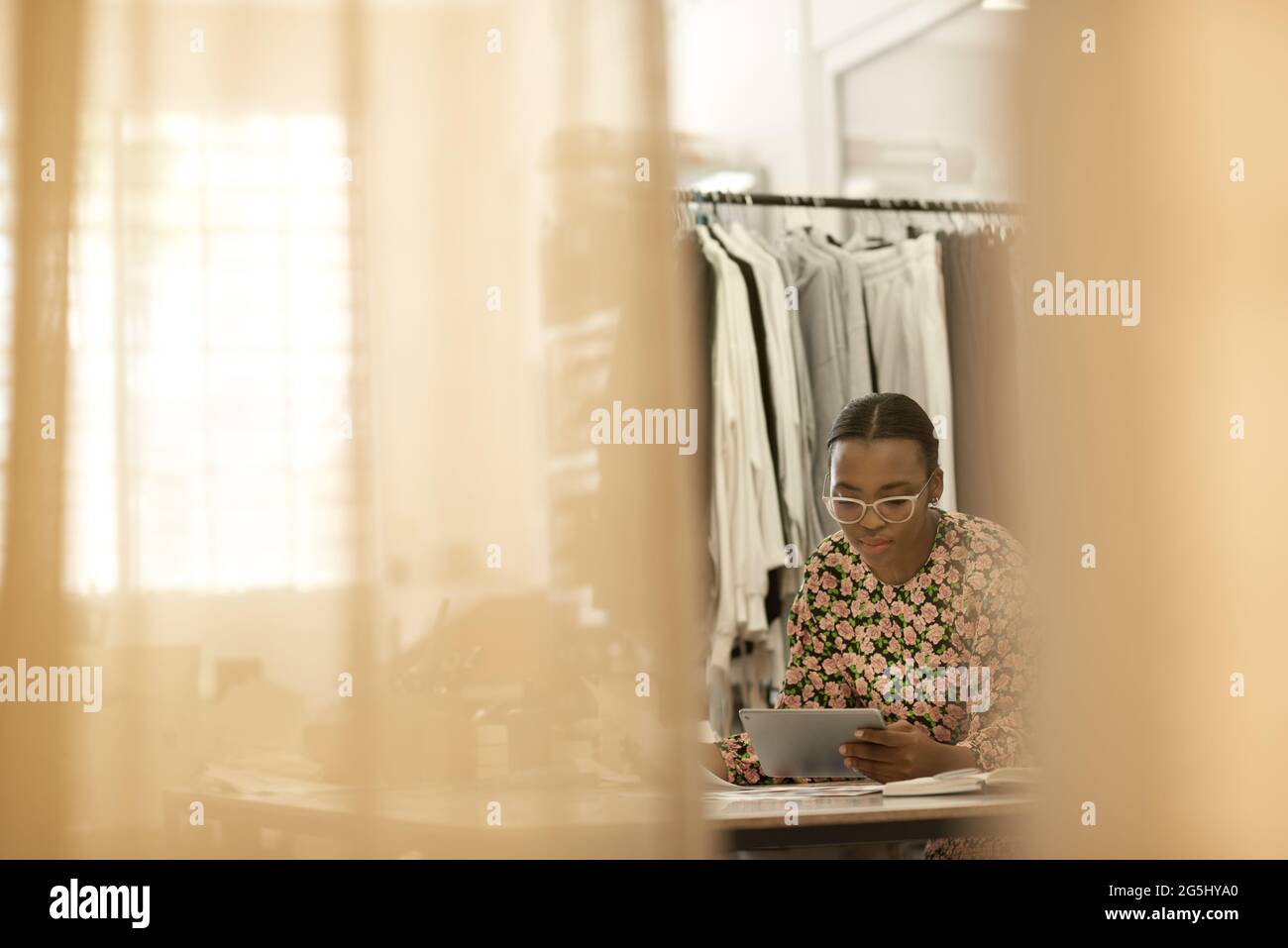 Diseñadora de ropa femenina africana trabajando en una tableta en la mesa del estudio Foto de stock
