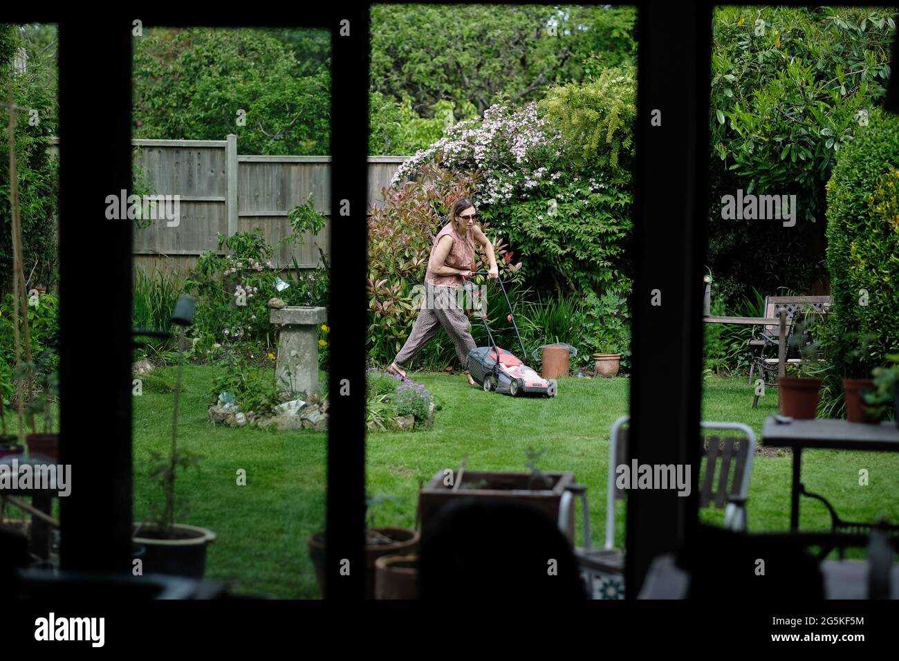 Una mujer segando su jardín suburbano en Bristol. Foto de stock