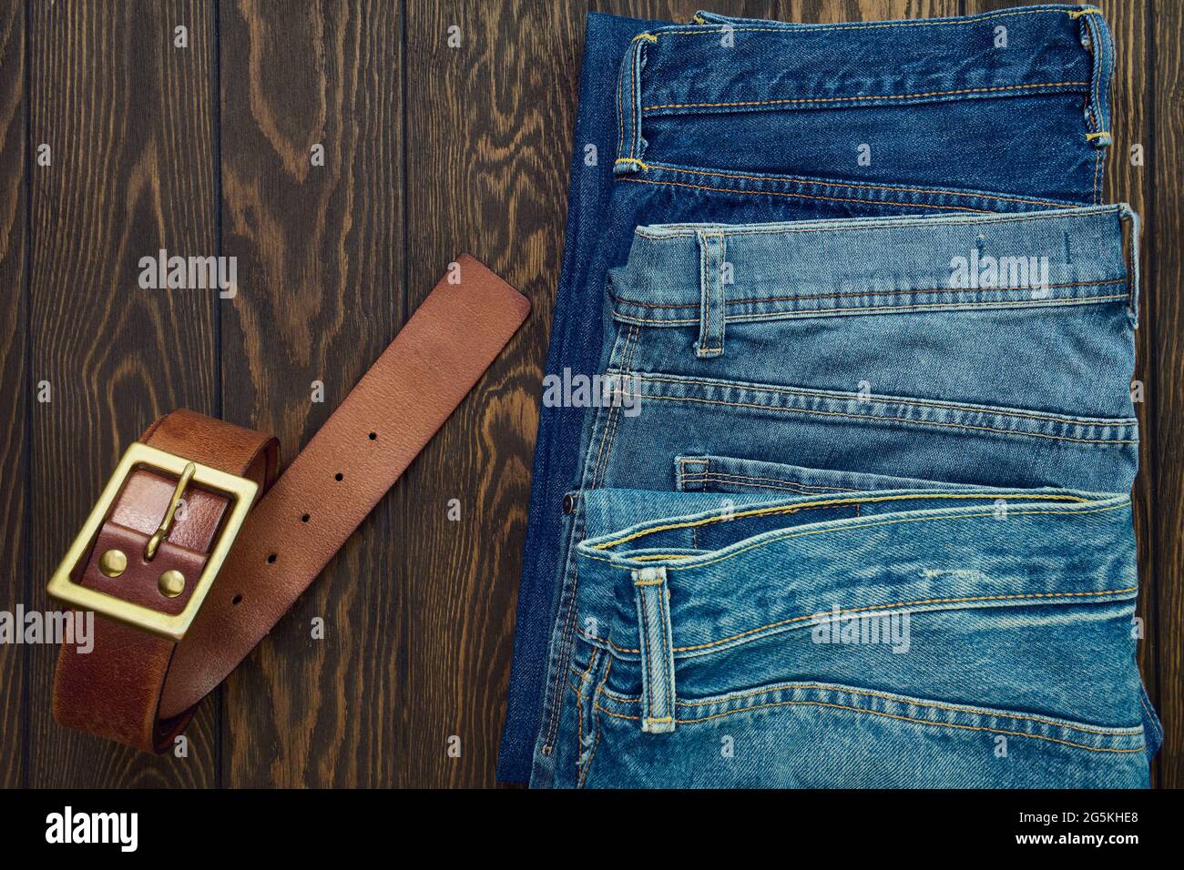 Fila de jeans para hombre y cinturón de piel sobre fondo de madera, vista  superior Fotografía de stock - Alamy