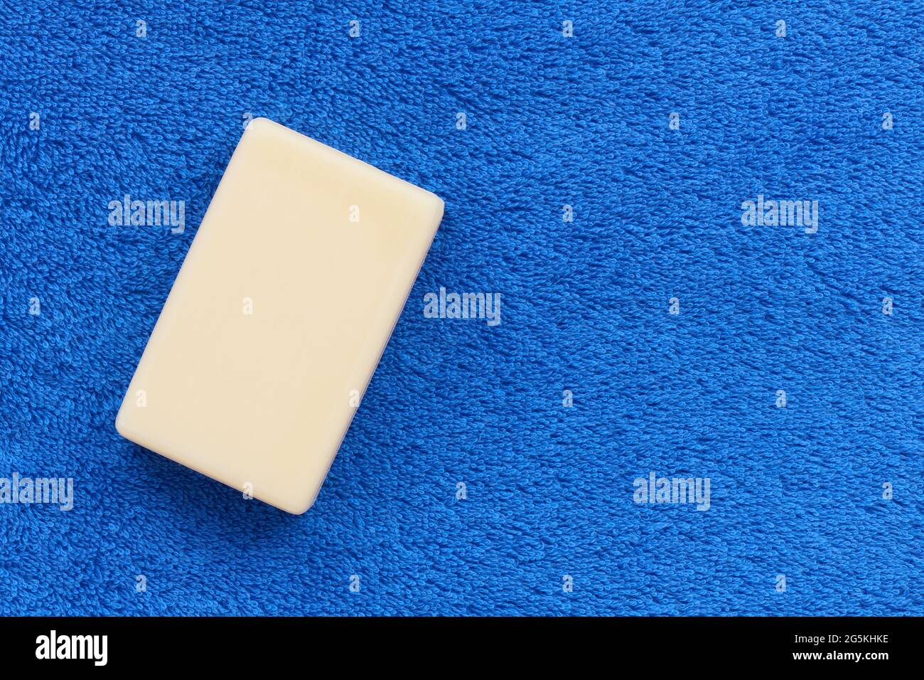 Barra blanca de jabón sobre suave toalla rústica azul con espacio de copia, concepto de higiene Foto de stock