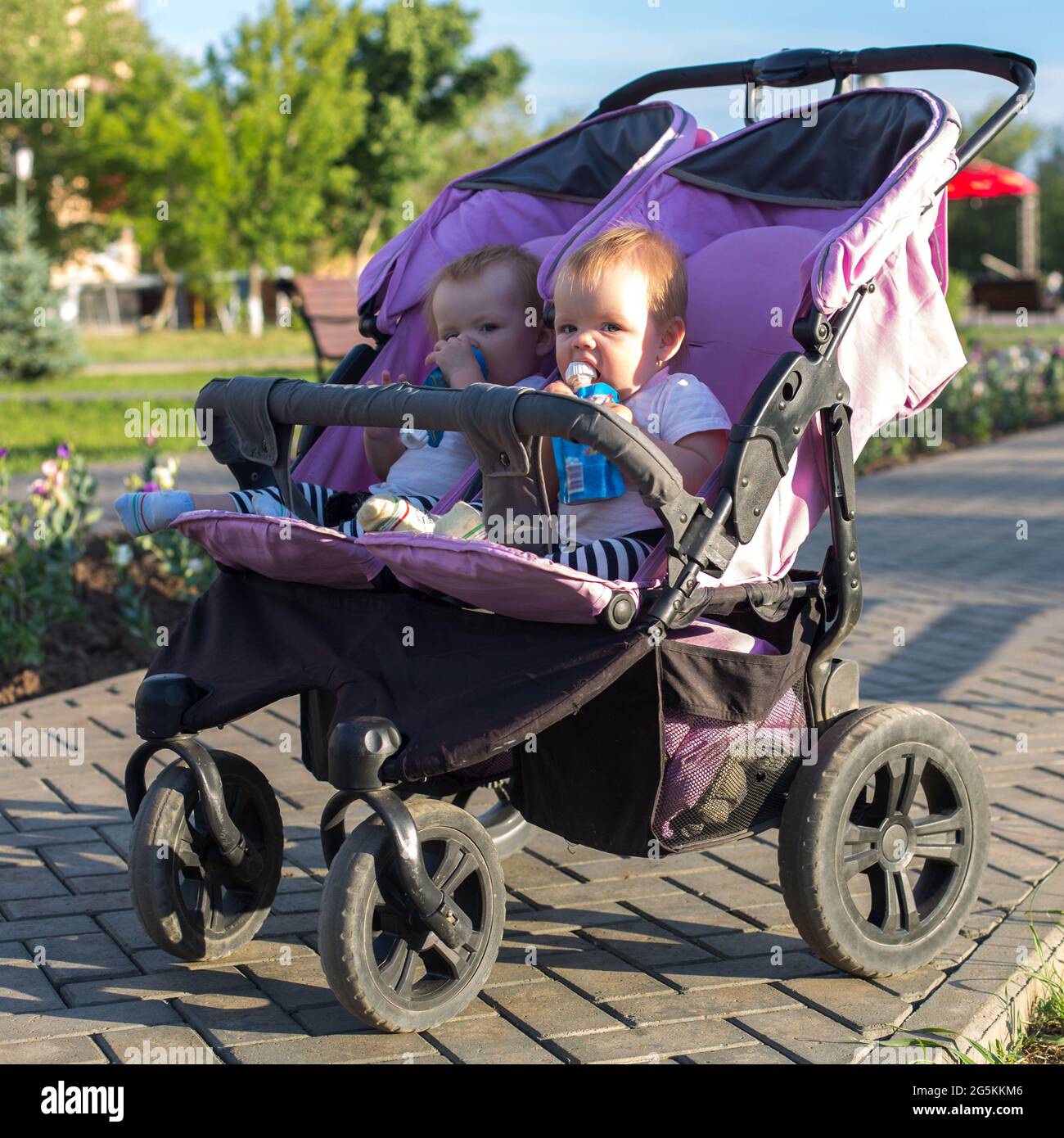 Gemelos en un cochecito para bebés en un paseo por el parque de la ciudad  en verano Fotografía de stock - Alamy