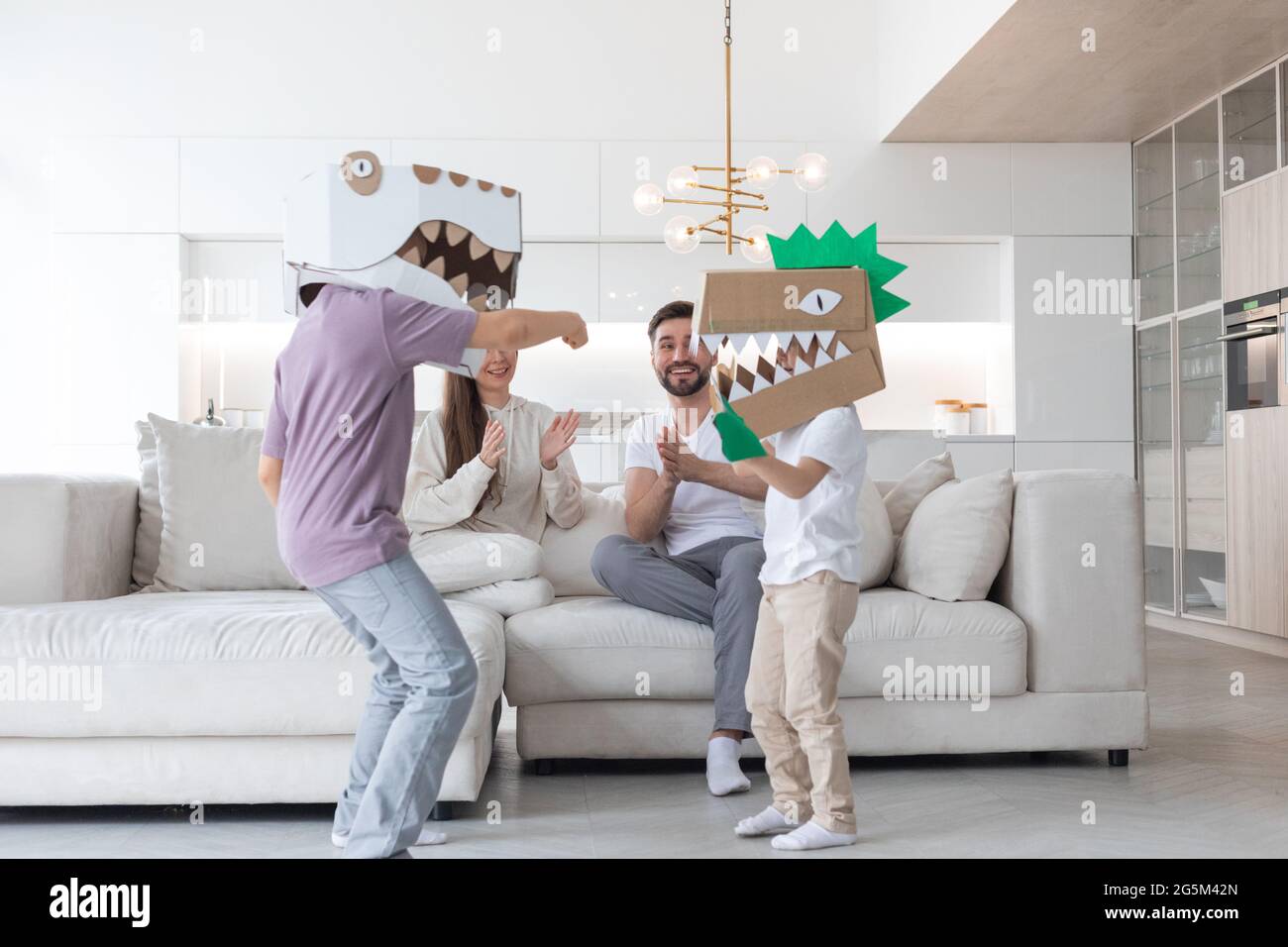 Feliz familia de padres y dos niños jugando dinosaurios en casa, niños  usando una máscara de cartón hecha a mano Fotografía de stock - Alamy