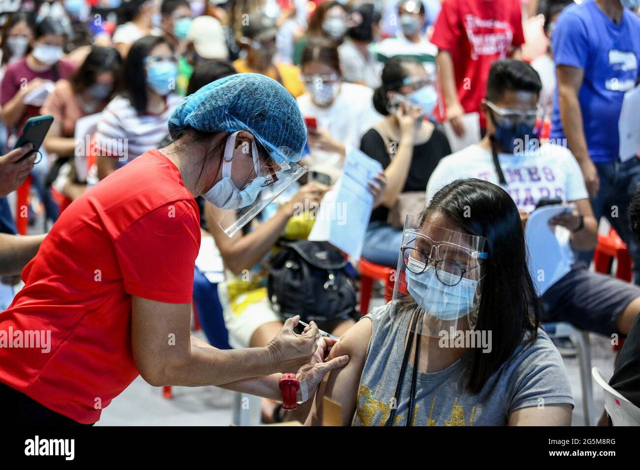 Un trabajador de la salud inocula a un paciente con la vacuna COVID-19 Pfizer-BioNTech dentro de un estadio deportivo convertido en un sitio temporal de vacunación en la ciudad de San Juan, Metro Manila, Filipinas. Foto de stock