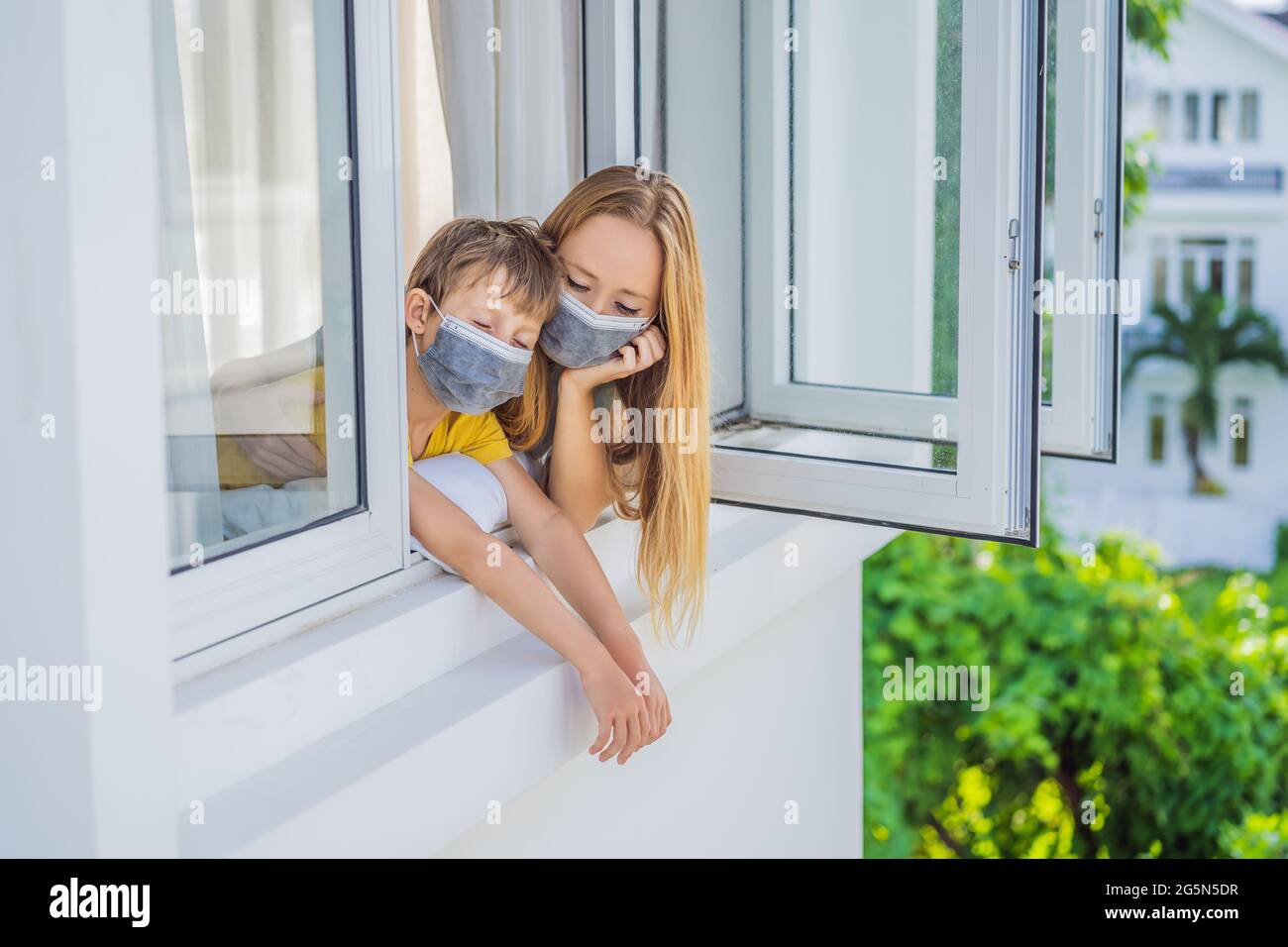 Madre e hijo extremadamente cansados mirando por la ventana, solo en casa. Autoaislamiento en casa, cuarentena por pandemia COVID 19. Problemas de salud mental Foto de stock