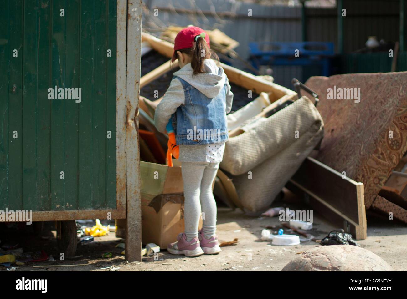 notificación Punto Médico Un niño en un junkyard. La chica está goteando en la basura. El niño  encontró el juguete en el montón de basura. La pobre niña está caminando  sola Fotografía de stock -