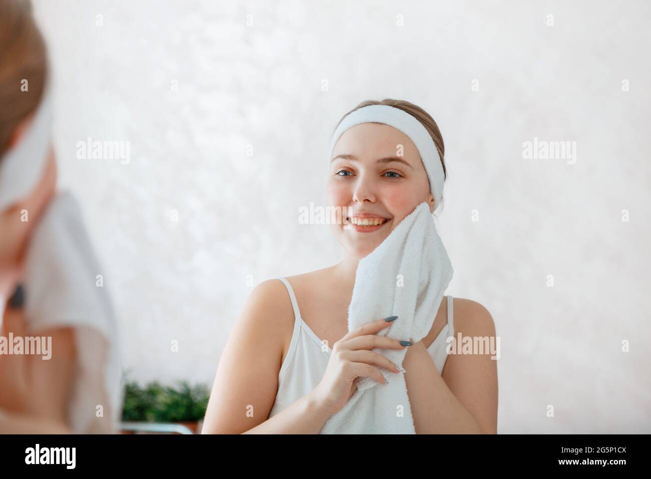 Una mujer joven se limpia la cara con una toalla blanca después de