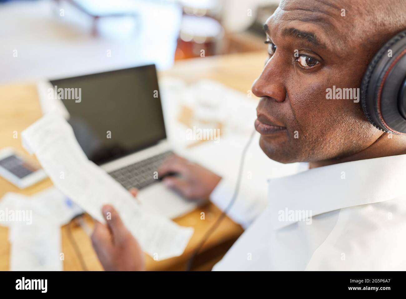 Hombre de negocios africano con recibo en la computadora haciendo contabilidad en la oficina de casa Foto de stock