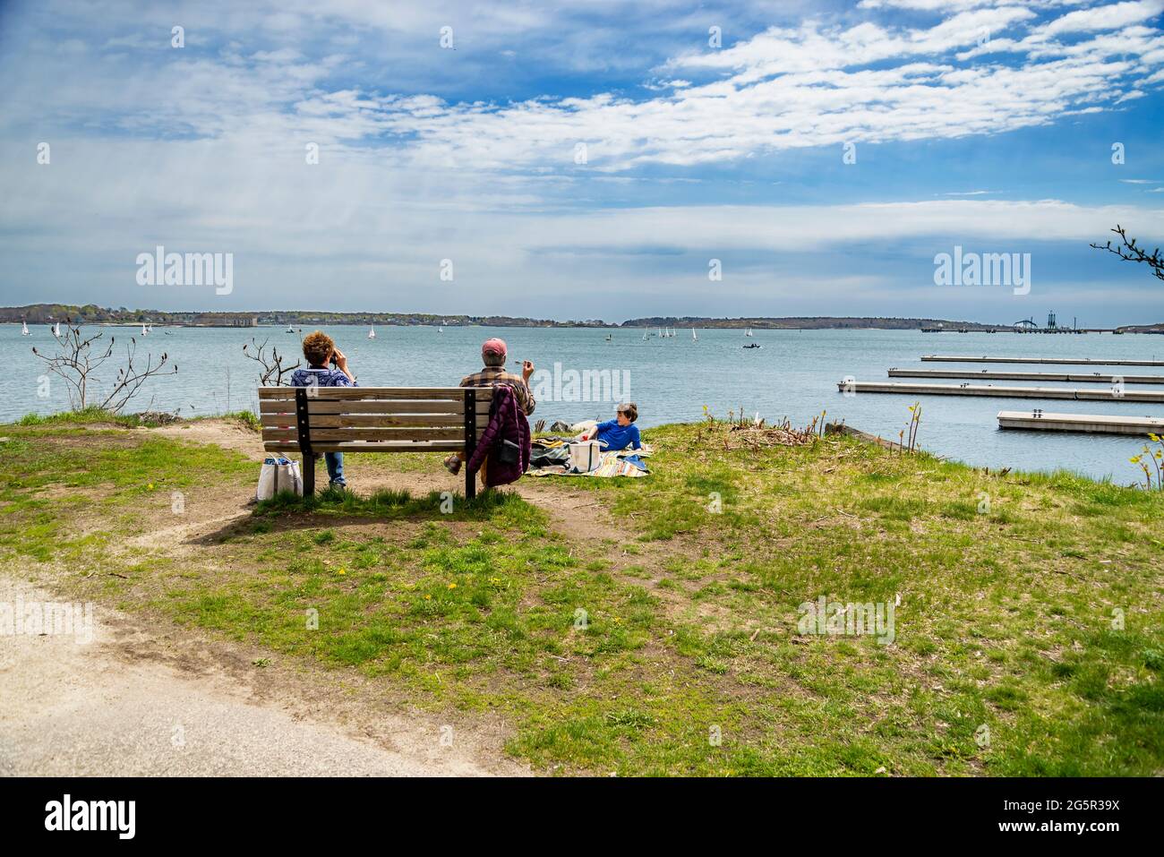 PORTLAND ME, 2 DE MAYO de 2021: Familia de tres personas sentadas en la costa en verano y viendo la hermosa vista al océano, en Portland, Maine Foto de stock