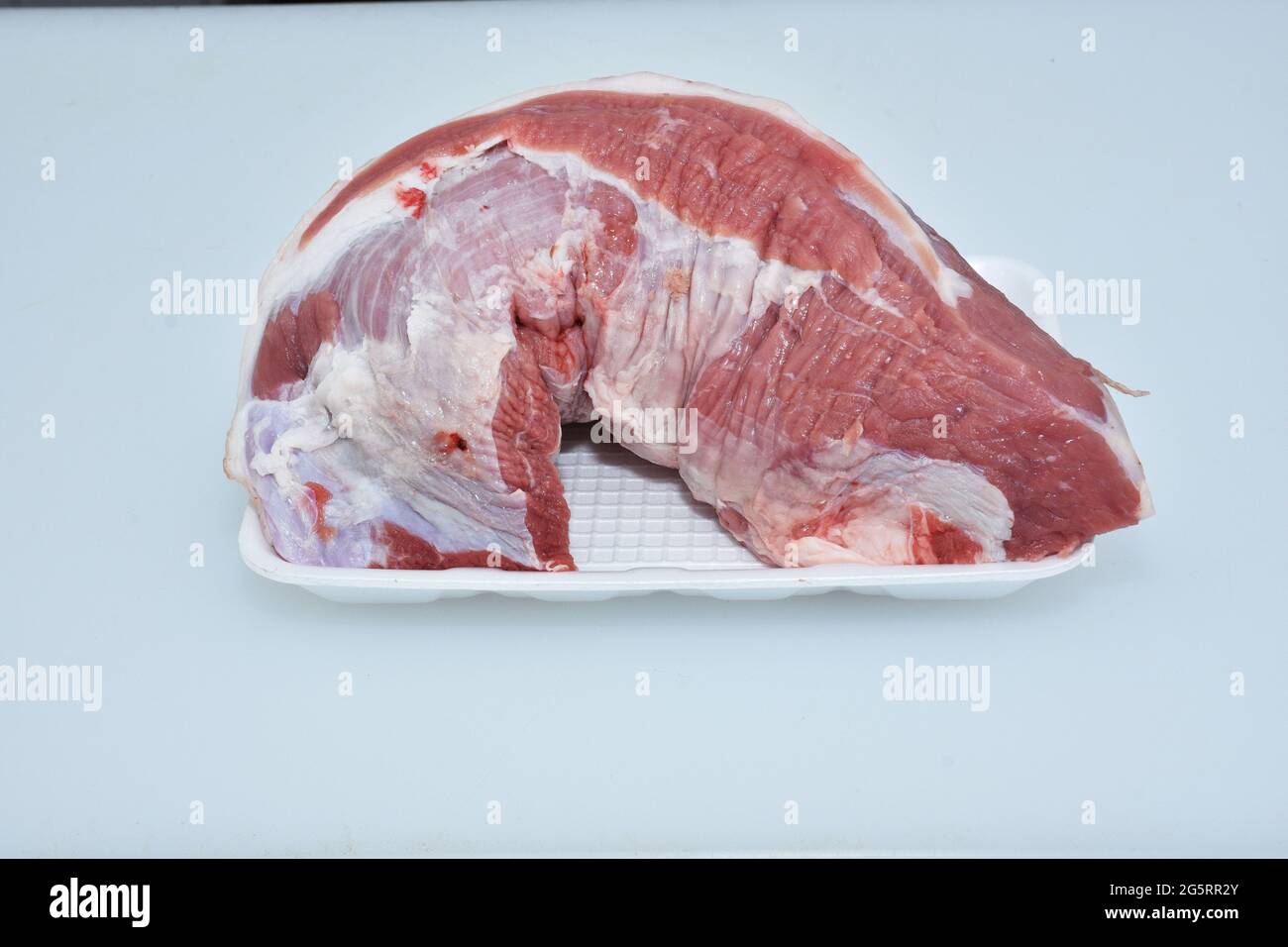 carne de lomo de cordero en plato de fondo blanco primer plano, carnero crudo, carnicero cortado Foto de stock