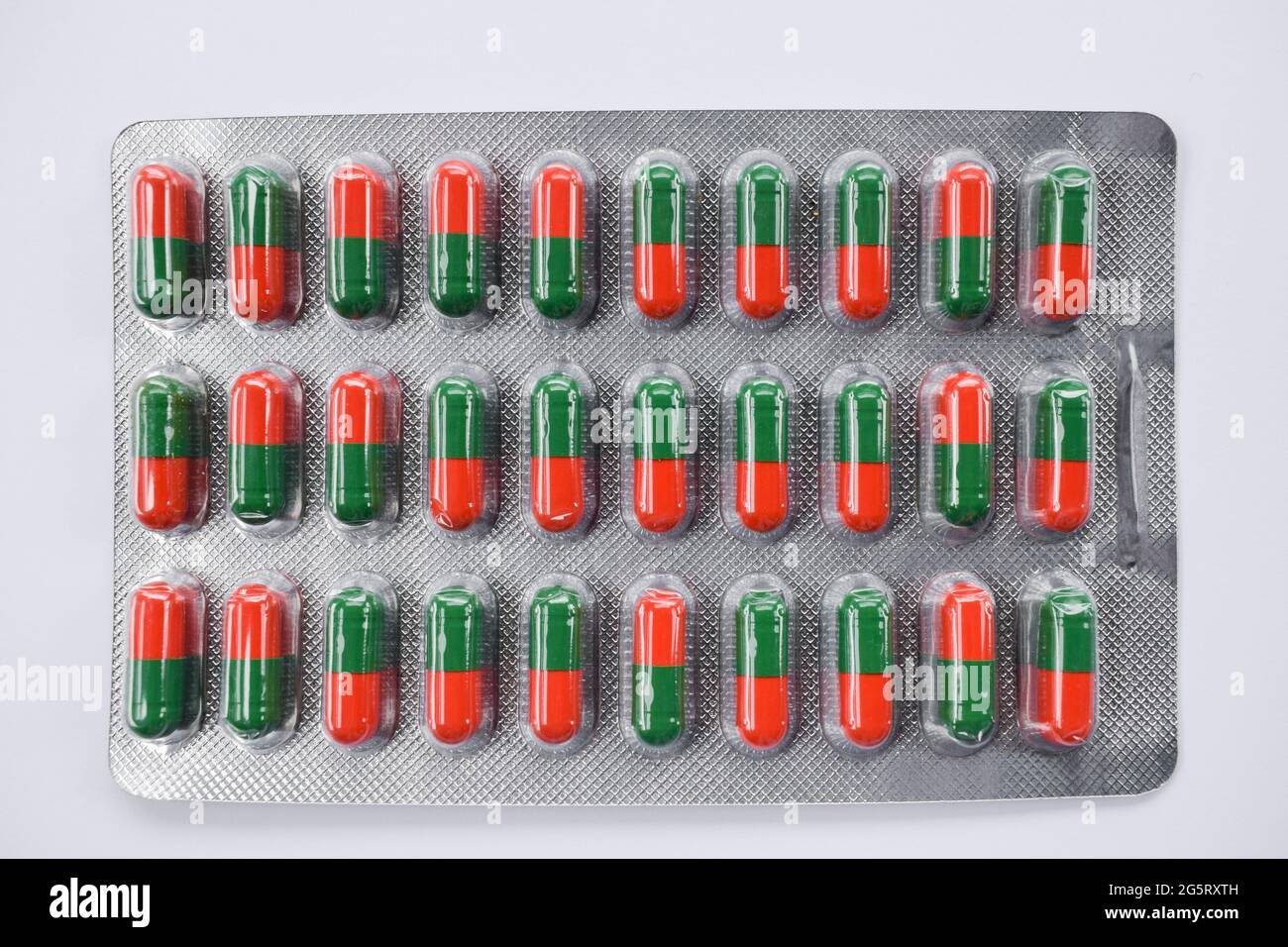 Cápsulas de color rojo y verde Fondo. Textura de las tabletas ayurvédicas para el alivio de los síntomas sinusales. Foto de stock