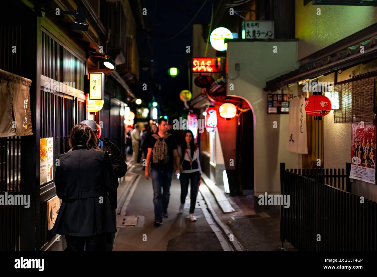 Kyoto, Japón - 16 de abril de 2019: Personas caminando por el distrito de Pontocho callejón calle estrecha en la noche oscura con faroles iluminados y restaurantes izakaya Foto de stock
