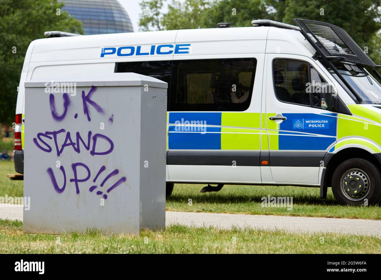 Londres, Reino Unido - 15 de junio de 2021: Graffiti anti-encierro mostrado en los muebles de la calle frente a una furgoneta de policía en el campo de protesta de Shepherds Bush. Foto de stock