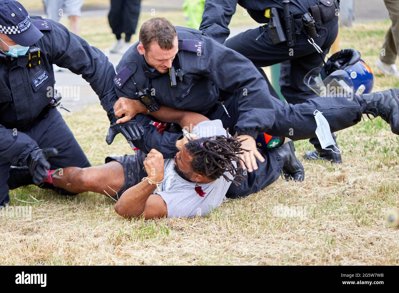 Londres, Reino Unido - 17 de junio de 2021: Un manifestante es atacado al suelo por la policía tras el desalojo del amoroso campo anti-encierro en Shepherds Bush Green. Foto de stock
