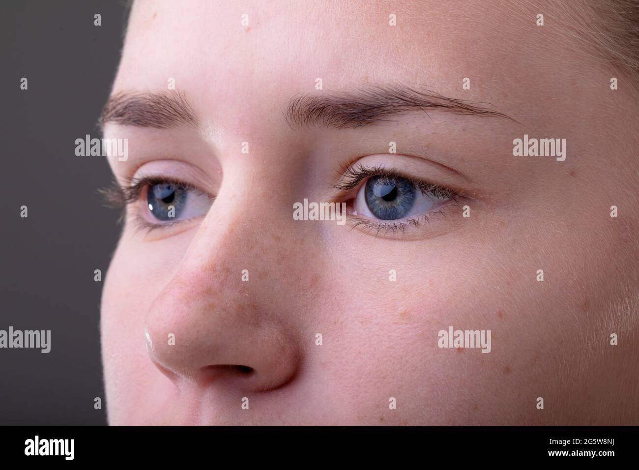 Primer plano de ojos azules de mujer de negocios caucásica aislados sobre fondo gris Foto de stock