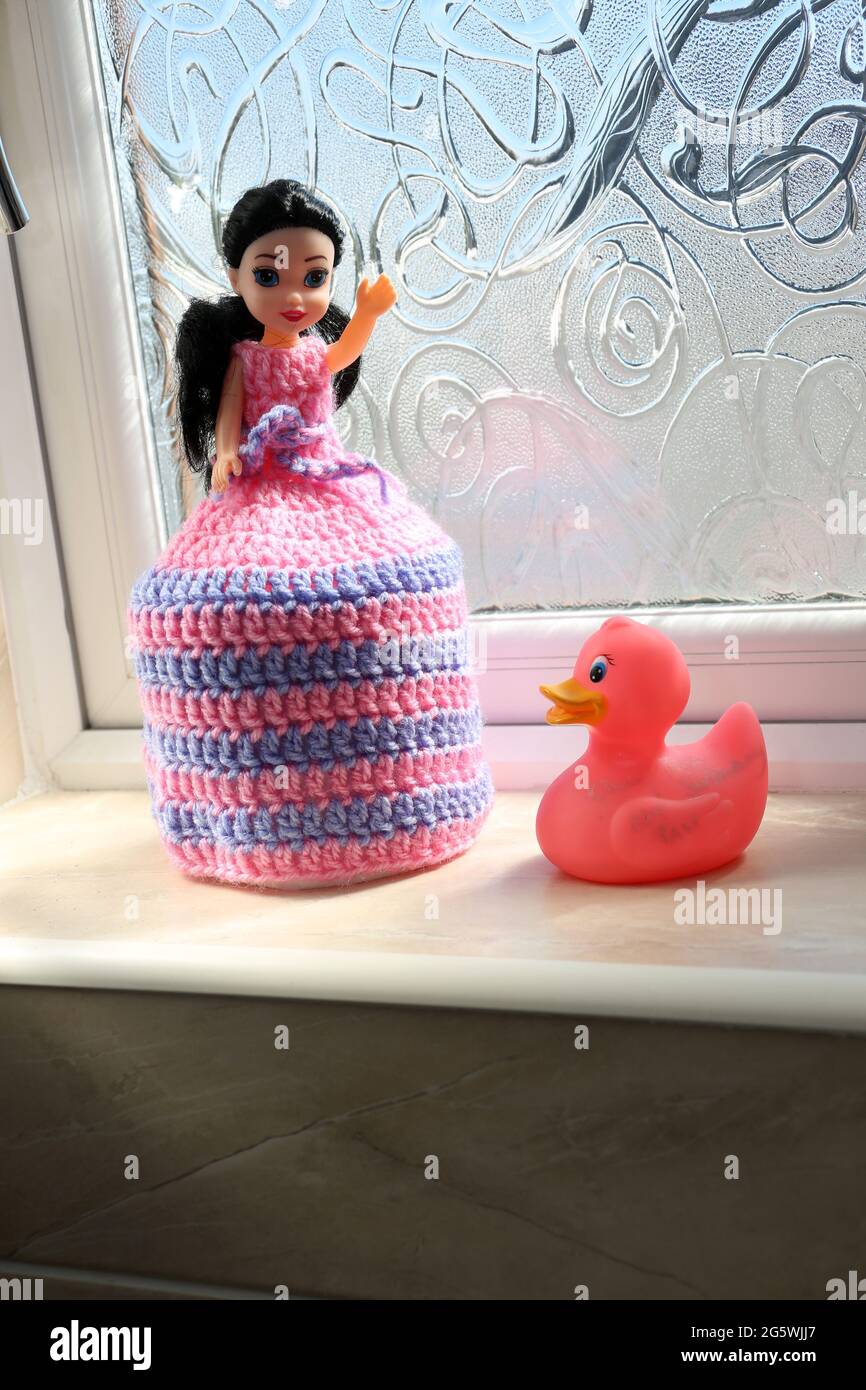 Muñeca de juguete con vestido de ganchillo que se extiende sobre un rollo  fresco de papel higiénico Fotografía de stock - Alamy