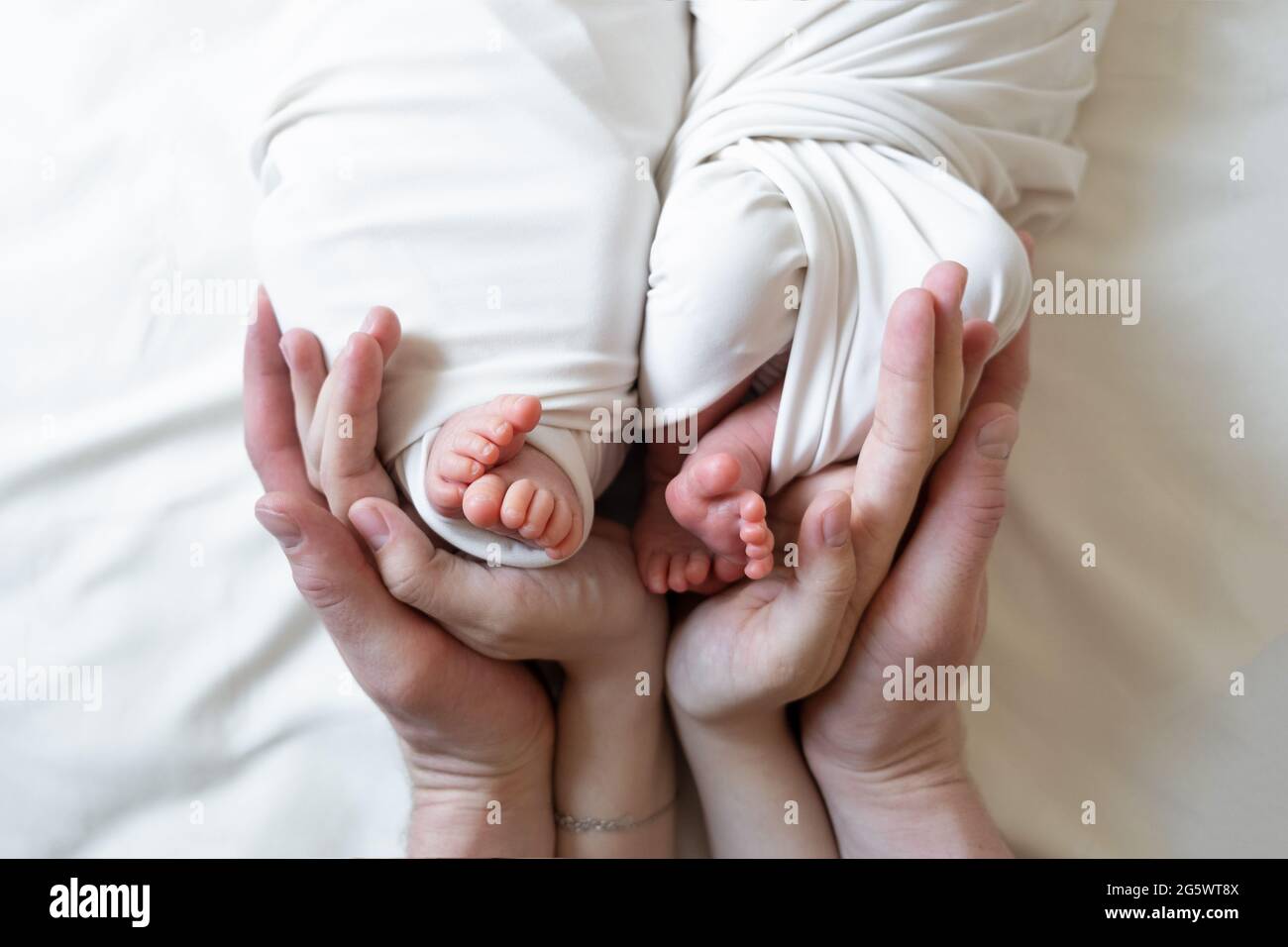 Las Manos De Mama Y Papa Sostienen Las Piernas Pequenas De Sus Dos Bebes Recien Nacidos Gemelos Fotografia De Stock Alamy