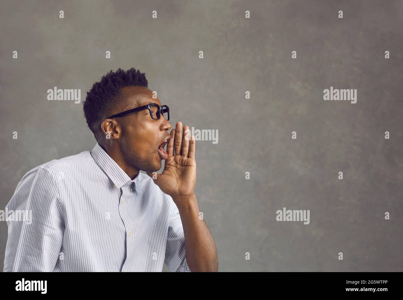 Un hombre afroamericano gritando poniendo la mano como un altavoz de estudio Foto de stock