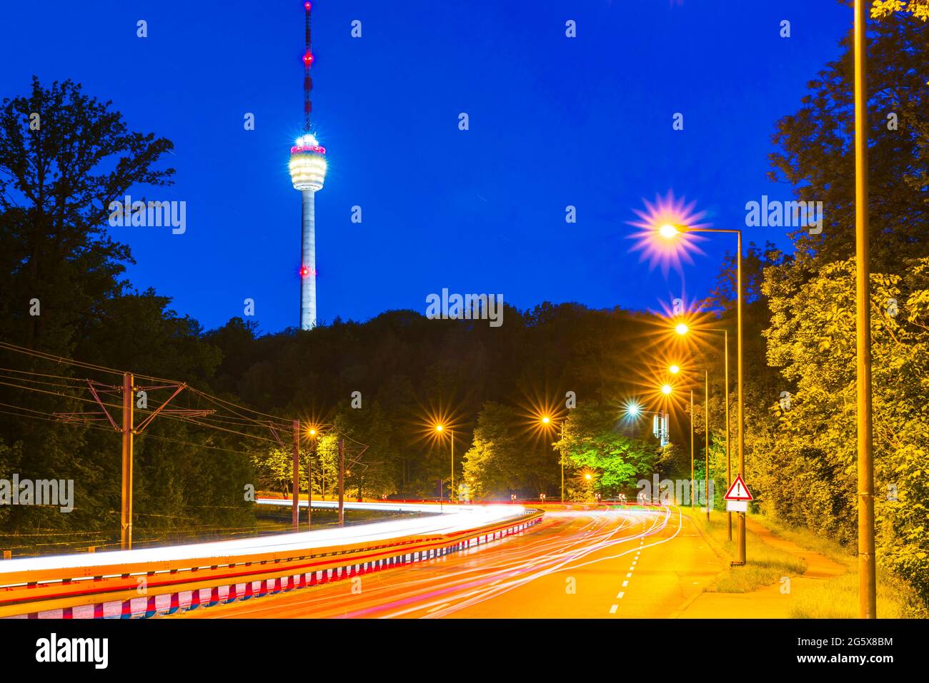 Alemania, Noche en la ciudad de stuttgart, calles iluminadas con tráfico que conducen al famoso edificio de la torre de televisión del horizonte Foto de stock