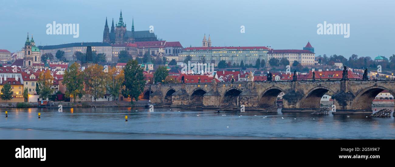 Praga - el panorama del Puente de Carlos, el Castillo y la Catedral desde el paseo marítimo sobre el río Vltava al atardecer. Foto de stock