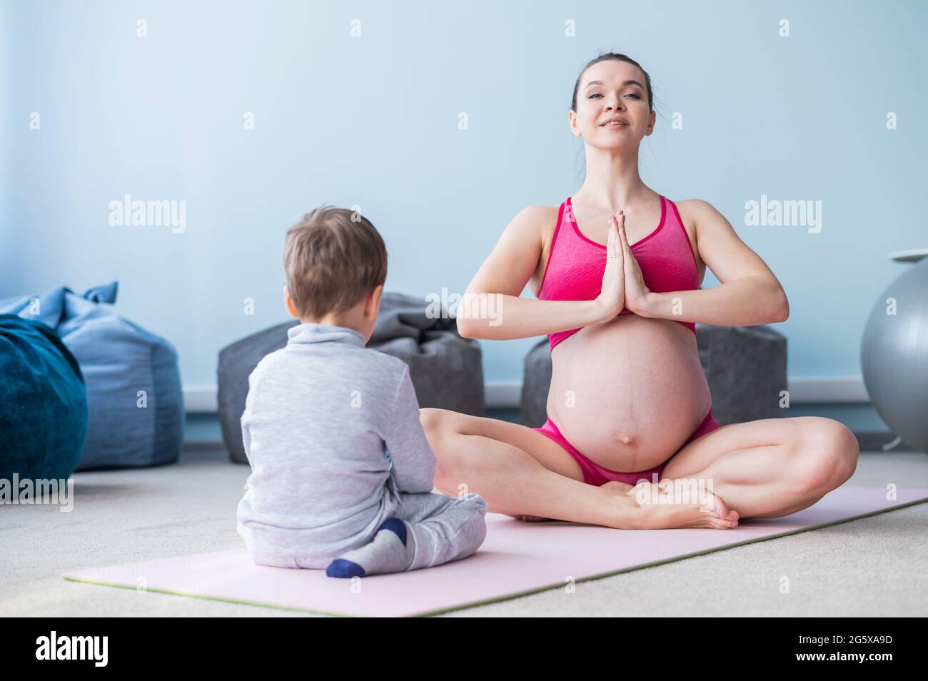 Una mujer embarazada en ropa deportiva está gimnasia en una estera su hijo. Niña de yoga con su hijo. Fitness mamá y bebé Fotografía stock Alamy