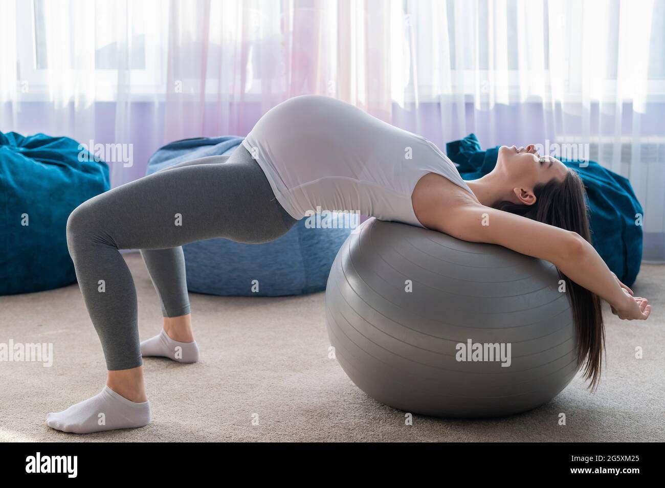 Una mujer embarazada miente con su espalda en una pelota de fitness. Una  mujer en el tercer trimestre entra para los deportes. Pilates para mujeres  embarazadas Fotografía de stock - Alamy