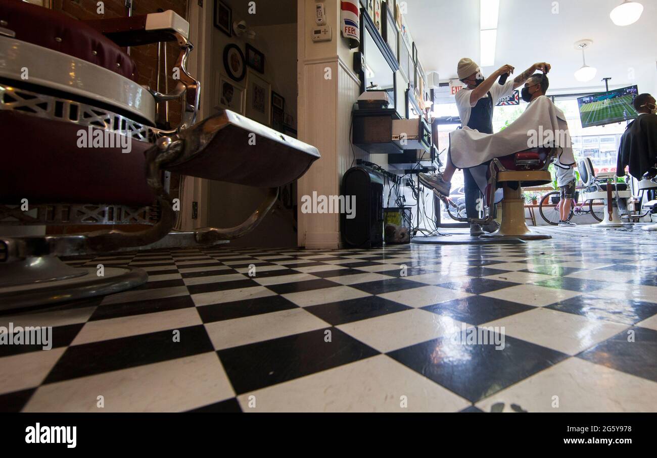 Toronto, Canadá. 30th de junio de 2021. Un barbero que usa una máscara facial corta el cabello de un cliente en un salón de belleza en Toronto, Ontario, Canadá, el 30 de junio de 2021. La provincia canadiense de Ontario permitió que la mayoría de las regiones reabrieran más negocios el miércoles a medida que se trasladaban al segundo paso del plan de reapertura de la provincia, incluyendo salones de cabello, salones de uñas y tiendas en centros comerciales. Crédito: Zou Zheng/Xinhua/Alamy Live News Foto de stock