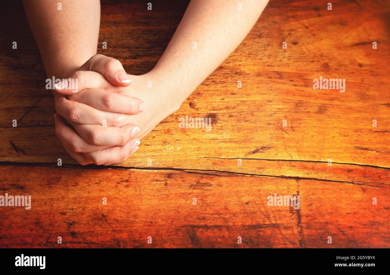 Una mujer orando con sus manos se aferró a una mesa de madera Fotografía de  stock - Alamy