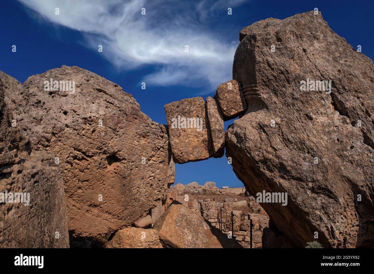 Suspendido en el espacio y tiempo en Selinunte, Sicilia, Italia: Pedazos de la mampostería griega antigua atrapados donde cayeron entre un tambor de columna inacabado y un corte parcial de la capital dórico de la roca sólida, en medio de las columnas caídas y otros trabajos de piedra de un templo derrumbado dedicado a Apolo o Zeus en la ciudad de Selinus o Selinous. La estructura, ahora conocida como Templo G, es el segundo templo griego más grande de Sicilia. Fue fundada en el año 530 a.C. pero estaba incompleta cuando Cartago saqueó a Selinus en el año 409 a.C. Más tarde colapsó, probablemente en un terremoto medieval. Foto de stock