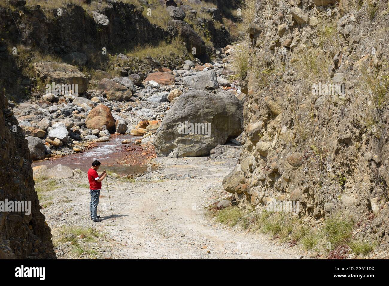 Camino polvoriento que conduce al rivulet del himalaya, un hombre con . Foto de stock