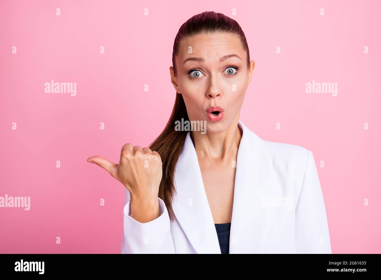 Foto de una mujer joven impresionada vestida de blazer blanco que apunta al  espacio vacío pulgar hacia el fondo aislado de color rosa pastel Fotografía  de stock - Alamy