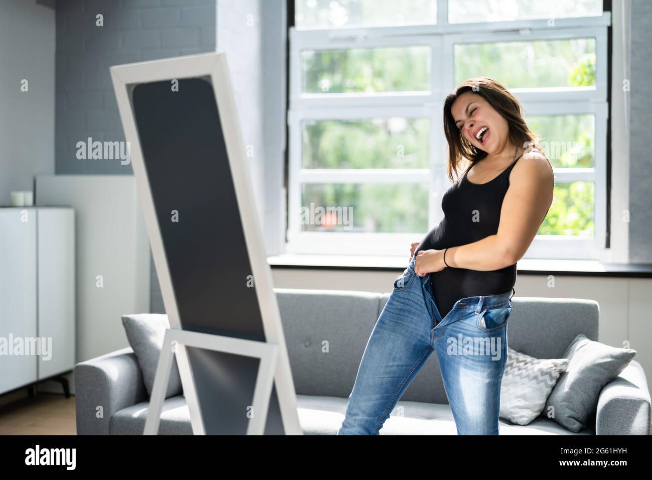 Mujer luchando con jeans ajustados. Aumento de peso Fotografía de stock -  Alamy