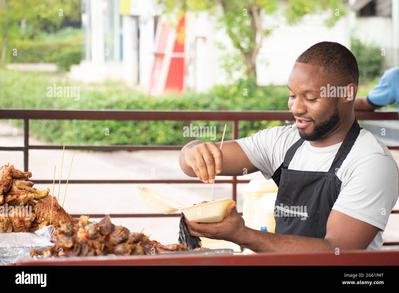 hombre africano que sirve pollo de barbacoa para llevar Foto de stock