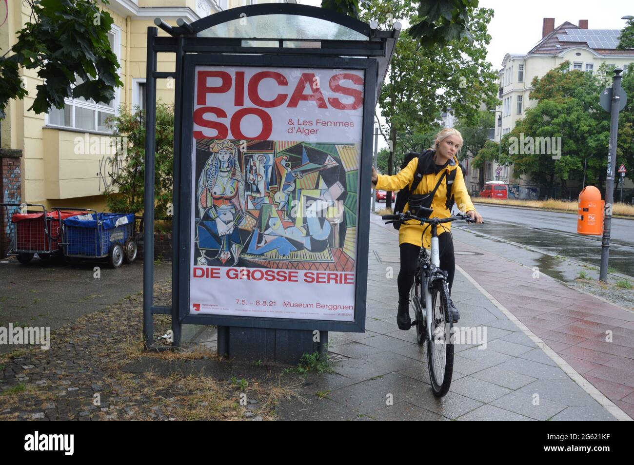 Pablo Picasso muestra publicidad en una parada de autobús y una joven con bicicleta en Saarstrasse en Berlín, Alemania - Junio 30 2021 - Museo Berggruen en Berlín muestra la exposición 'Picasso & Les Femmes d'Alger' 21.05.2021 a 29.08.2021. Foto de stock