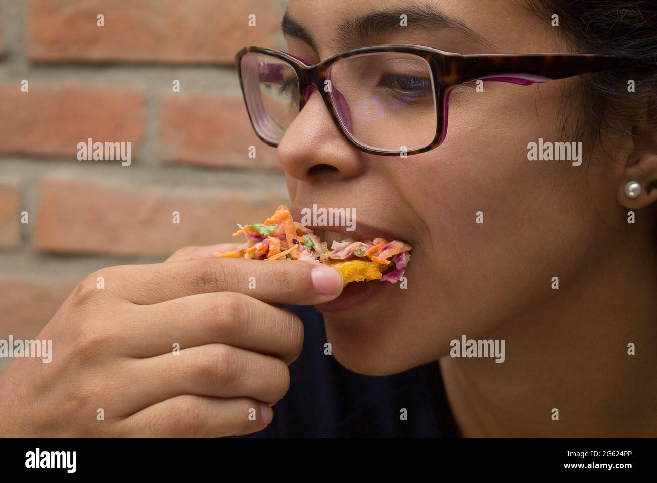 Una chica latina come Tostones con ensalada de zanahoria rallada, col, lechuga, mayonesa. Los patacones son típicos de la gastronomía del Caribe Foto de stock