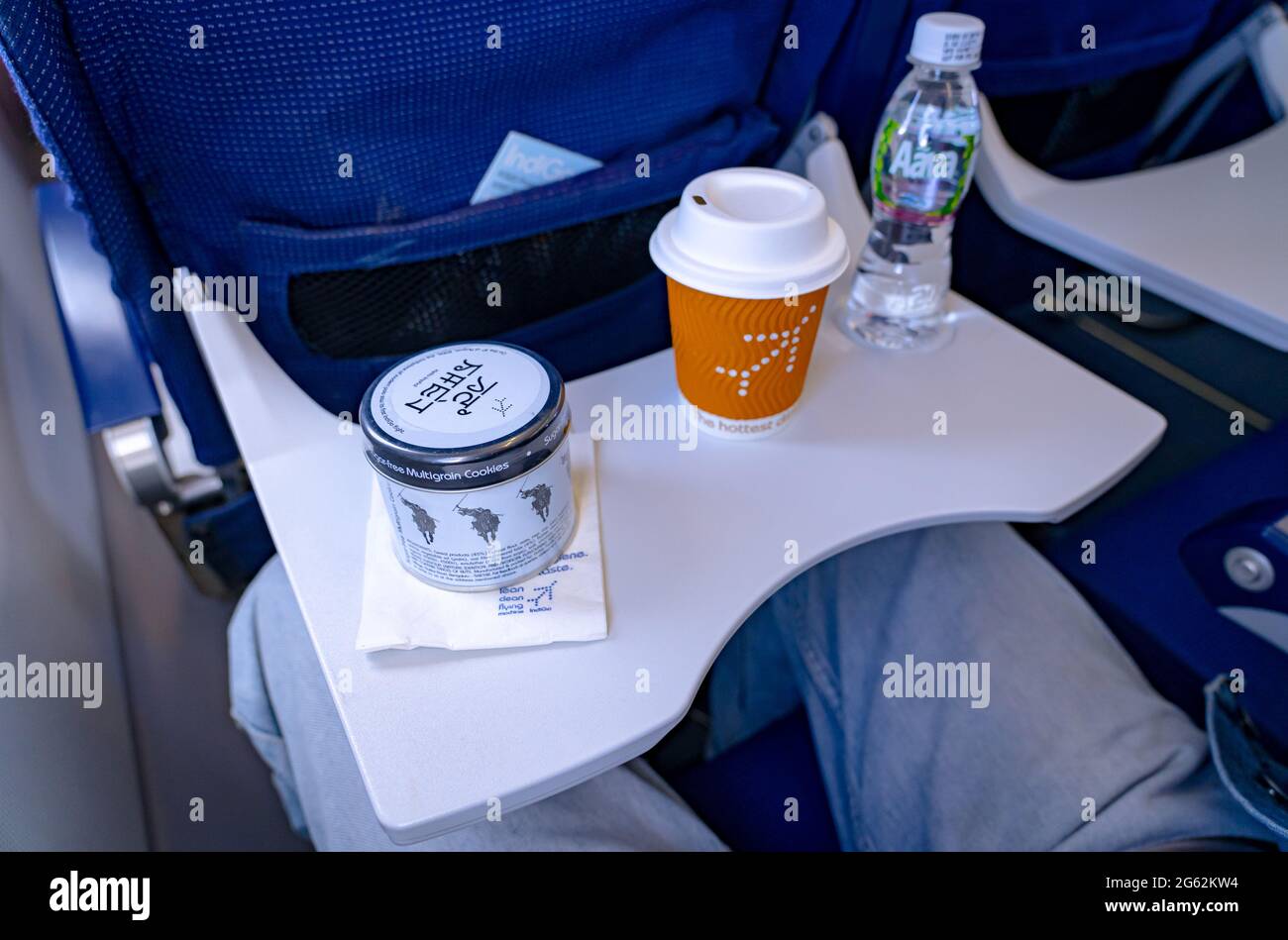 Una lata de galletas multigrano sin azúcar, café y una botella de agua sirvió como parte de la comida en vuelo en las aerolíneas Indigo. Foto de stock