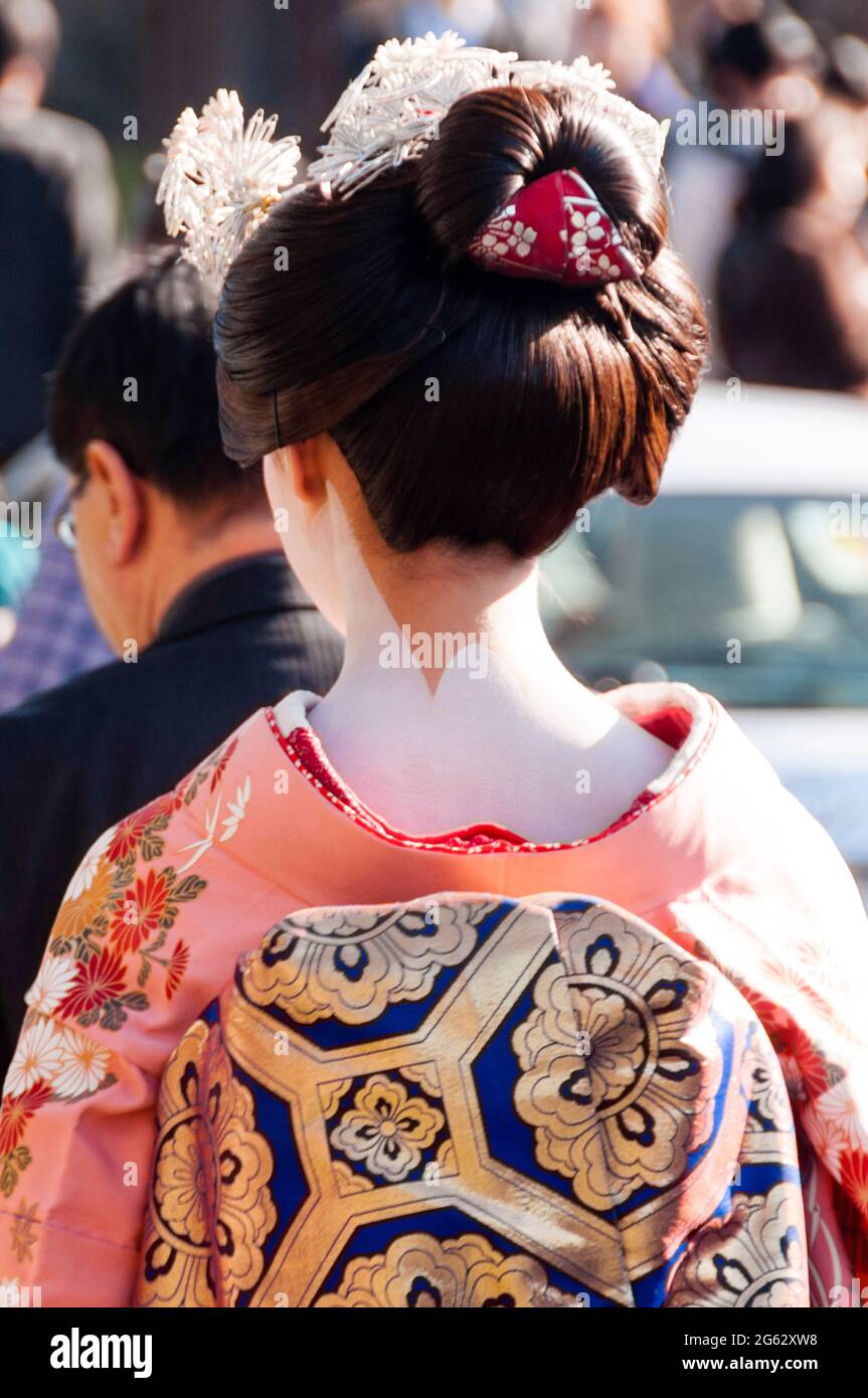 Un hombre con un kimono japonés en la cabeza se para frente a una pared que  dice 'geisha'.
