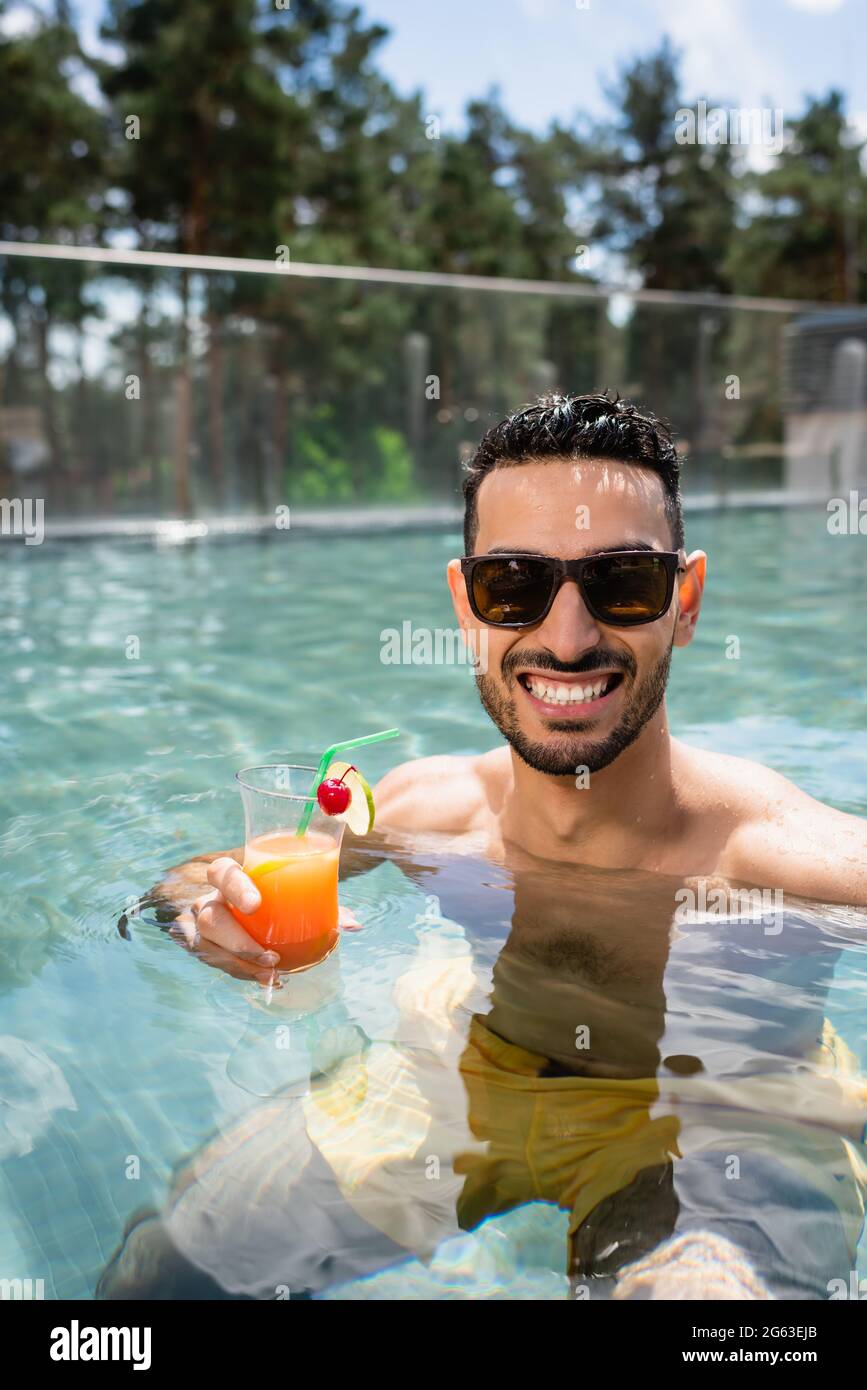 agradó al hombre musulmán en las gafas de sol relajándose en la piscina con  un cóctel refrescante Fotografía de stock - Alamy
