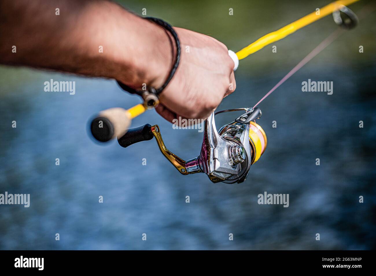 Pescador mano sosteniendo caña de pescar con carrete. Carrete de