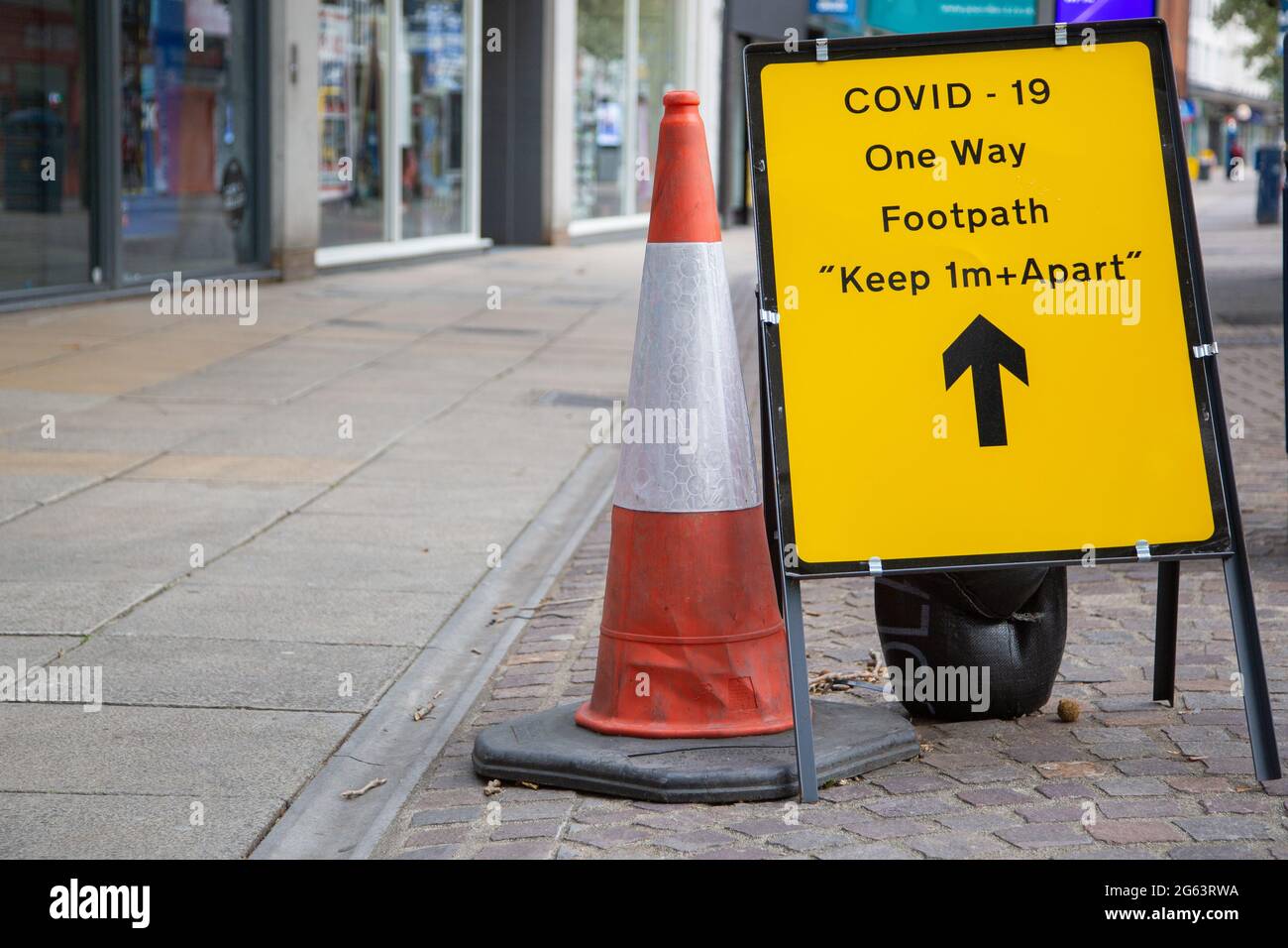 Una señal de advertencia de Covid 19 en una calle alta en inglés que advierte a las personas que se deben permanecer separadas durante la pandemia del coronavirus Foto de stock