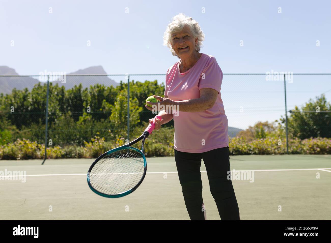 Retrato de una mujer mayor del cáucaso jugando al tenis en la pista sosteniendo raqueta de tenis Foto de stock
