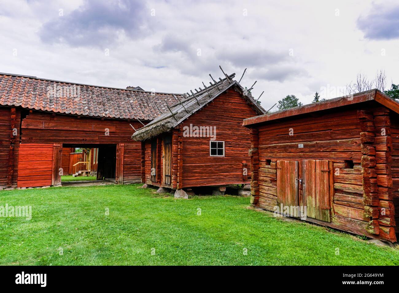 Gamla Uppsala, Suecia - 24 de junio de 2021: Casas de campo idílicas rojas en el país sueco con prados verdes en un hermoso día de verano Foto de stock