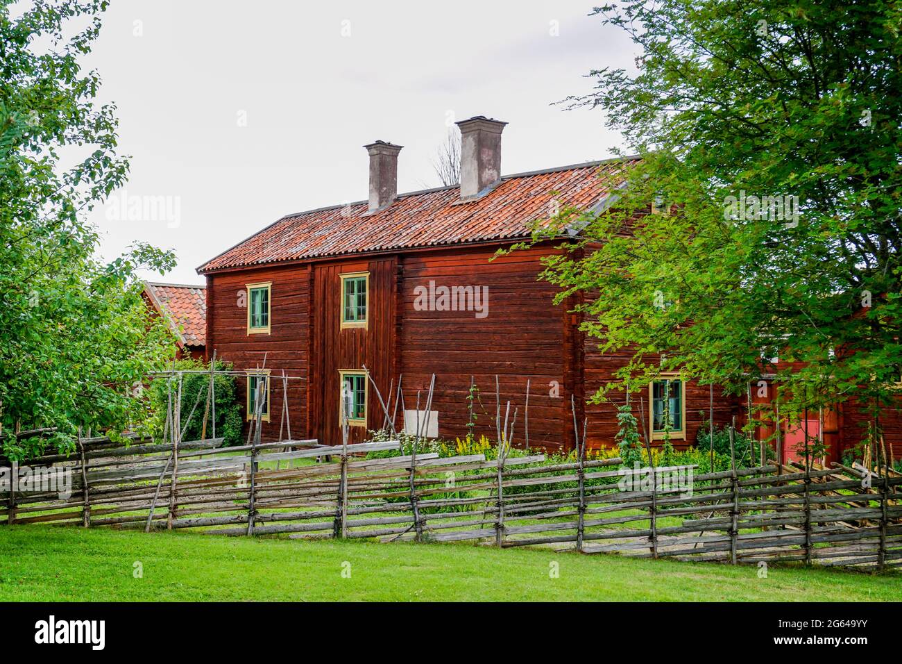 Gamla Uppsala, Suecia - 24 de junio de 2021: Casas de campo idílicas rojas en el país sueco con prados verdes en un hermoso día de verano Foto de stock