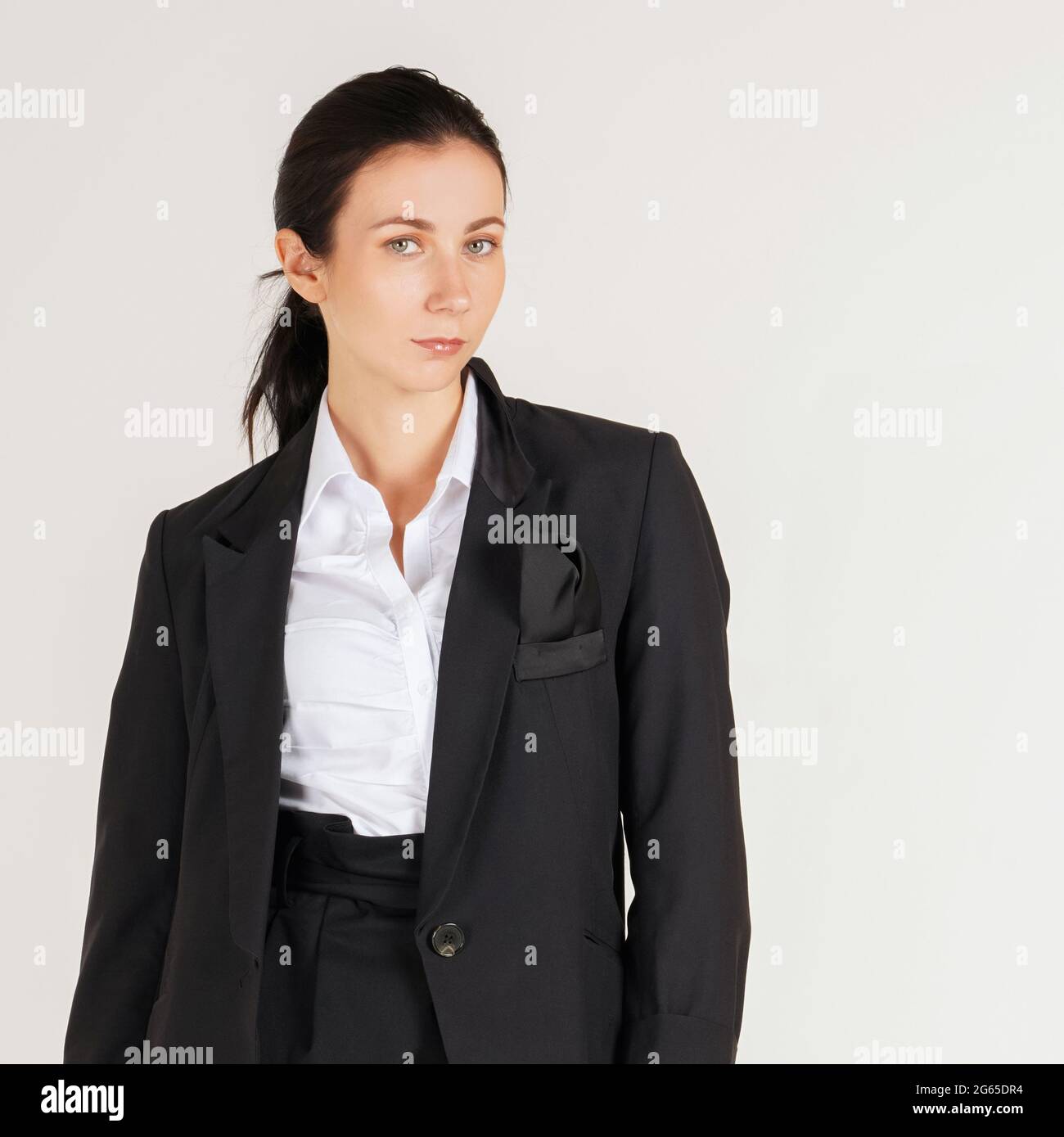 Joven mujer de negocios cauasiana con camisa blanca y traje negro de pie en  una escena de fotografía blanca. Retrato sobre fondo blanco con luz de  estudio Fotografía de stock - Alamy