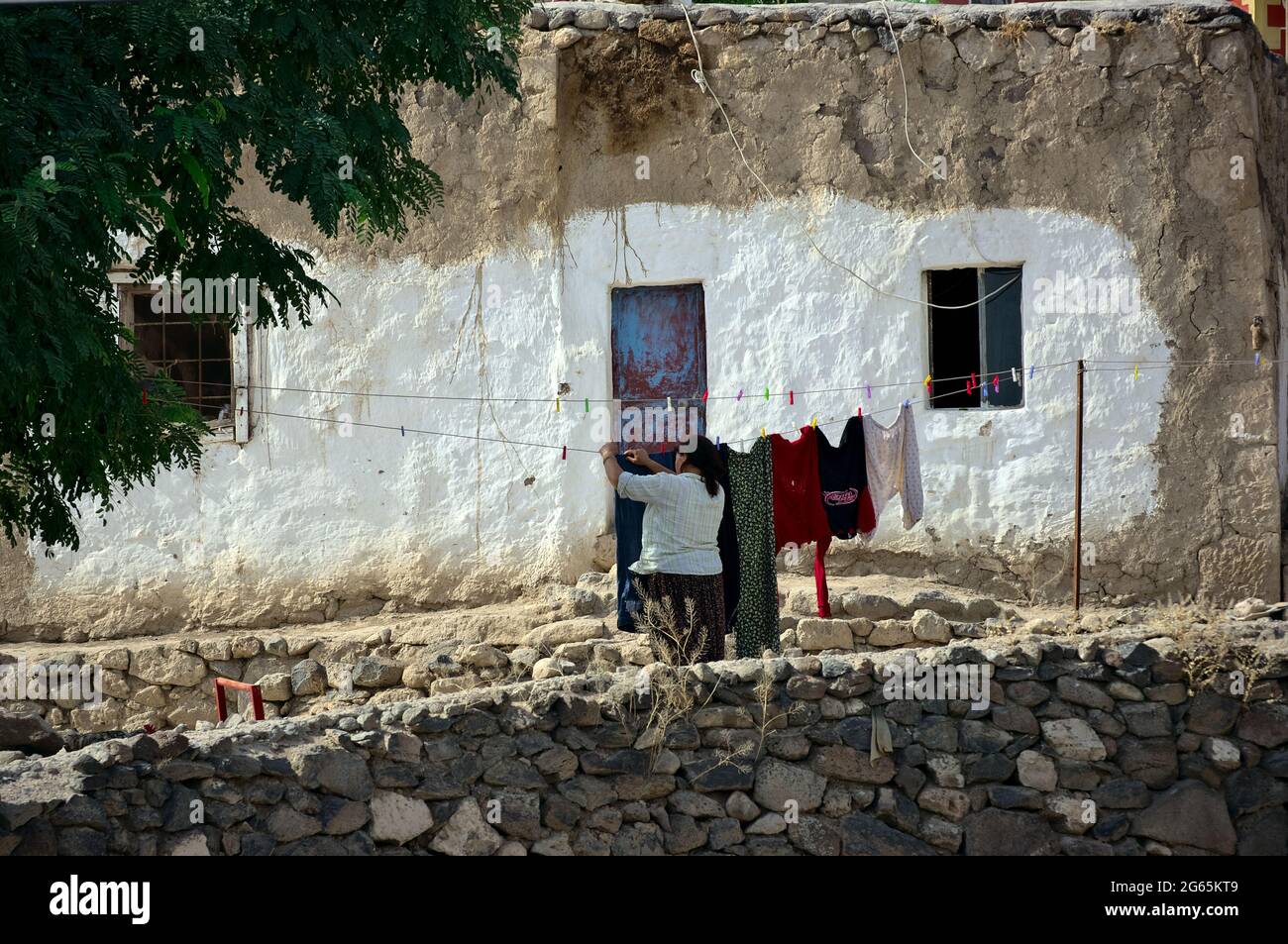 Cultura y arquitectura país de Turquía Una mujer que cuelga fuera de la ropa en frente de la casa rústica encalada Capadocia Fotografía de stock -