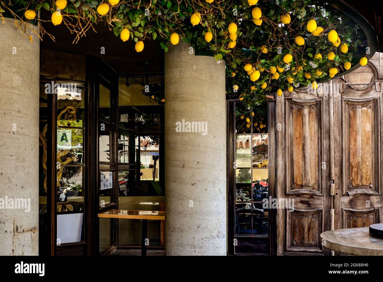 Entrada al elegante Allegro Italian Bar and Grill con puertas de madera vintage en el patio y decoración de plantas de limón en Little Italy, San Diego, CA Foto de stock