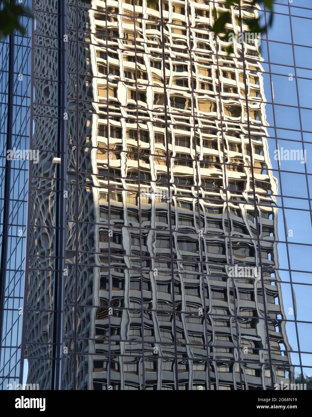 Un edificio de oficinas alto que se refleja en el cristal de un rascacielos moderno de la ciudad Foto de stock