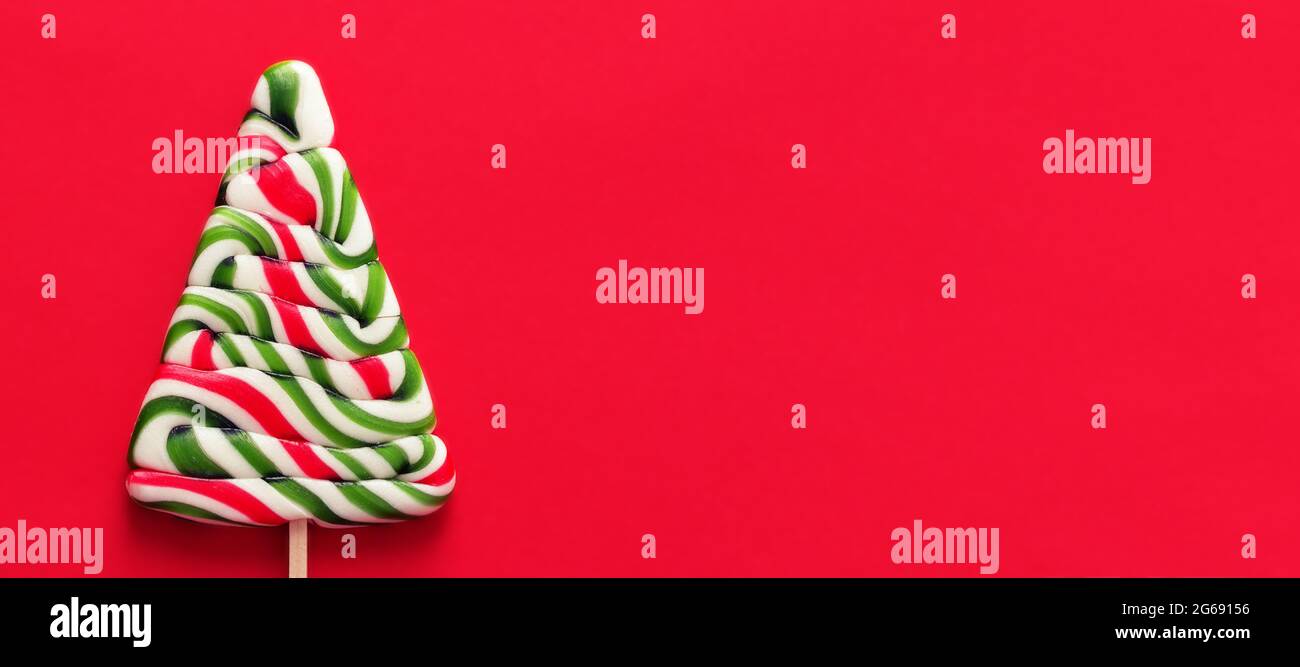 Bandera con caramelo rojo verde y blanco de Navidad sobre fondo rojo. Feliz año nuevo tarjeta de felicitación con opyspace Foto de stock